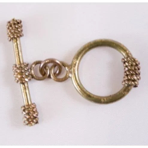 Gold-colored jewelry toggle with a circular design and a cylindrical accent on a white background